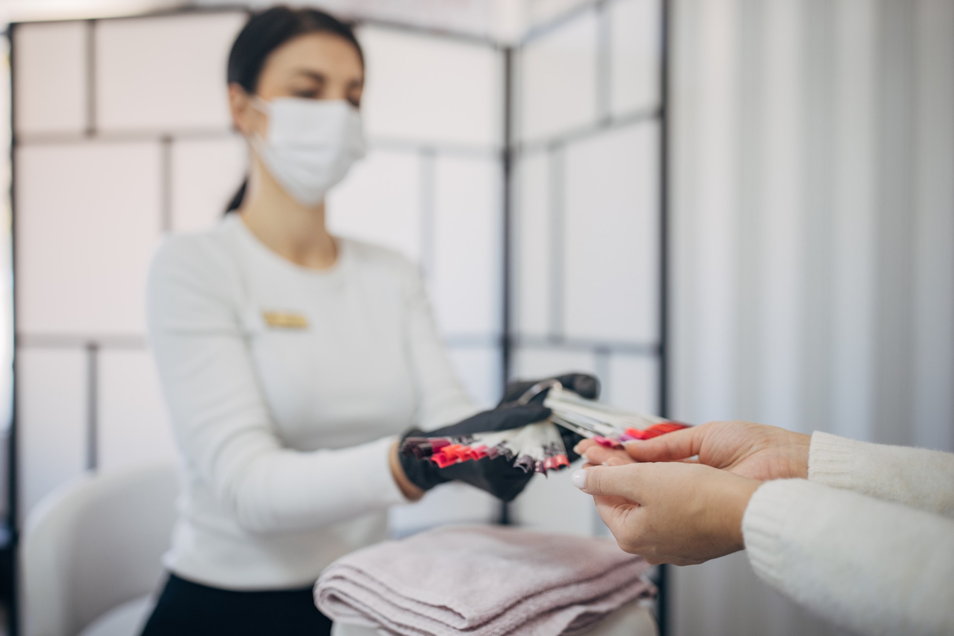 Manicurist at salon presenting nail color options to client